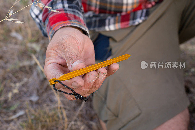 一个手粗的人握住并检查着他的现代帐篷钉