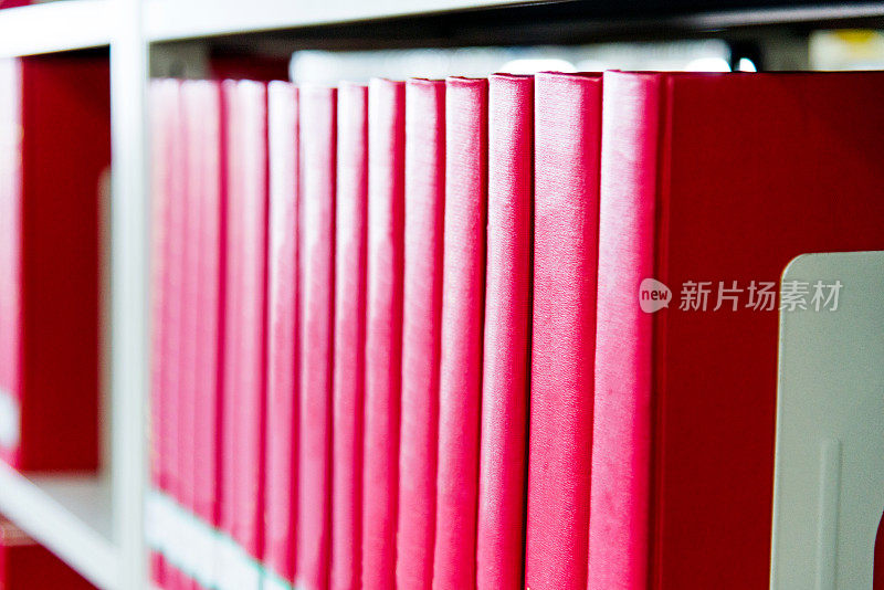 书架上有许多红色精装书