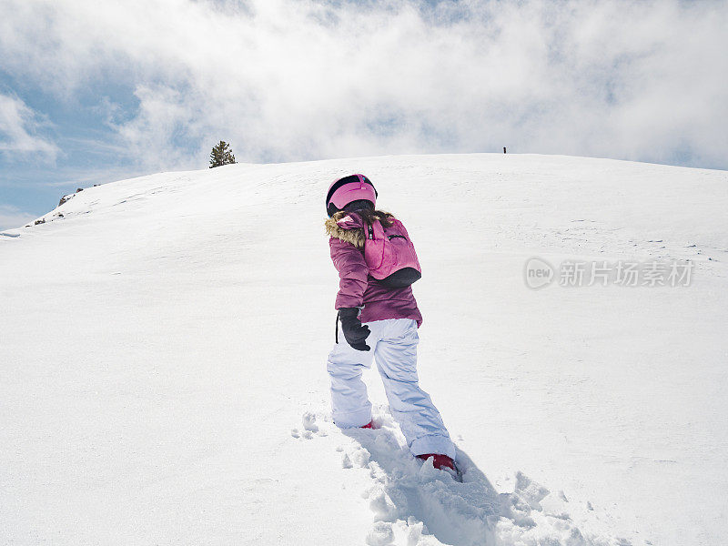 穿着滑雪服的女孩在雪地里行走