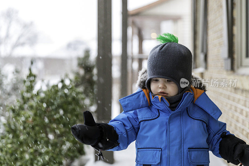 穿着蓝色冬装的小男孩和雪玩