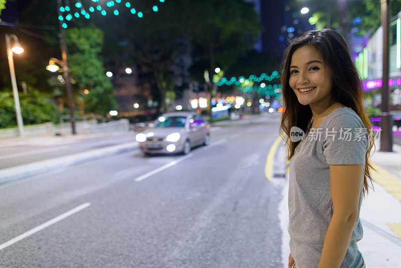 年轻美丽的亚洲女人的肖像漫步在城市街道晚上在吉隆坡，马来西亚