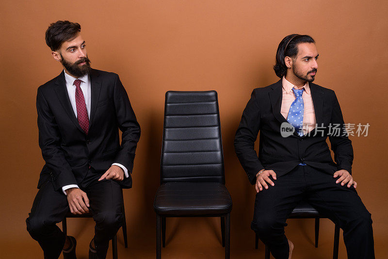 工作室拍摄的多民族的三个留着胡子的商人在有色背景下一起等待采访