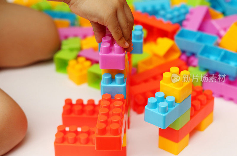 儿童的手构建塑料玩具积木与模糊的背景