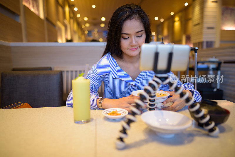 年轻美丽的亚洲女游客在泰国曼谷的餐厅里用手机拍视频
