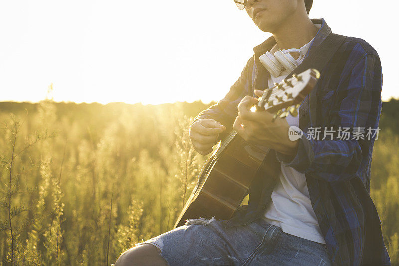 一个年轻人坐在草地上弹吉他