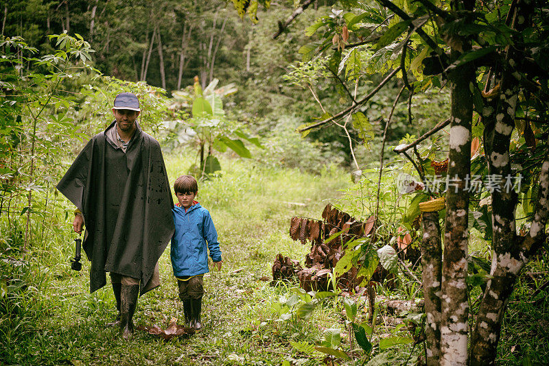 疲惫而悲伤的小男孩和父亲走在丛林里