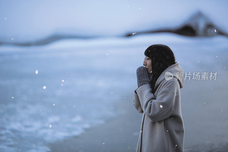 年轻女子站在结冰的池塘边