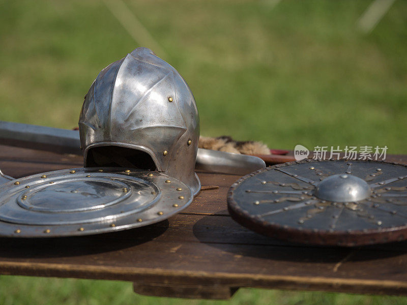 头盔，盾牌和中世纪金属盔甲和武器，户外木制桌子