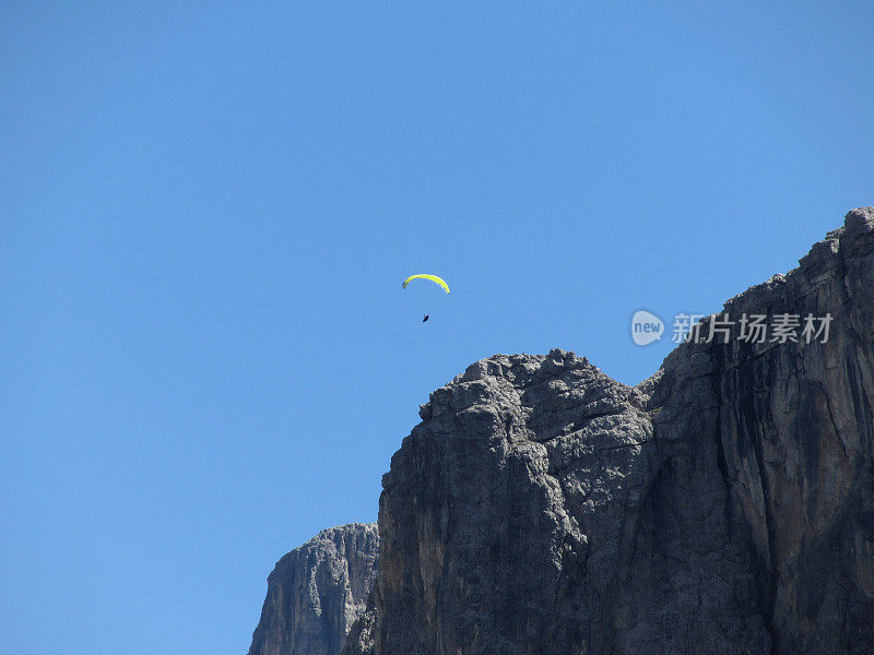 一个带着黄色降落伞的滑翔伞在意大利高山附近飞行。白云石山脉、意大利