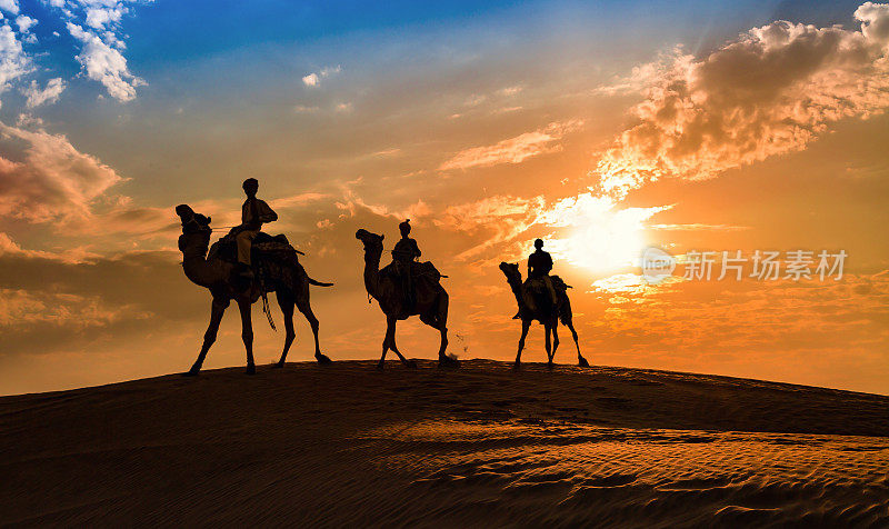 日落时分，印度拉贾斯坦邦贾伊萨尔默的塔尔沙漠，骆驼商队的剪影。