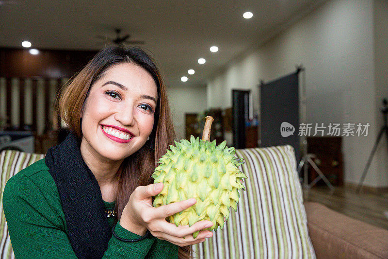 一个女人微笑着玩弄头发，拿着水果