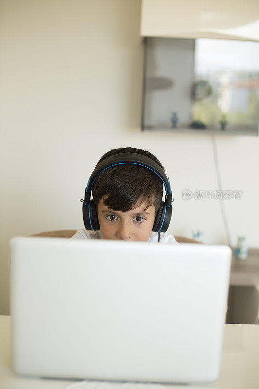 男孩戴着耳机在电脑上玩电子游戏