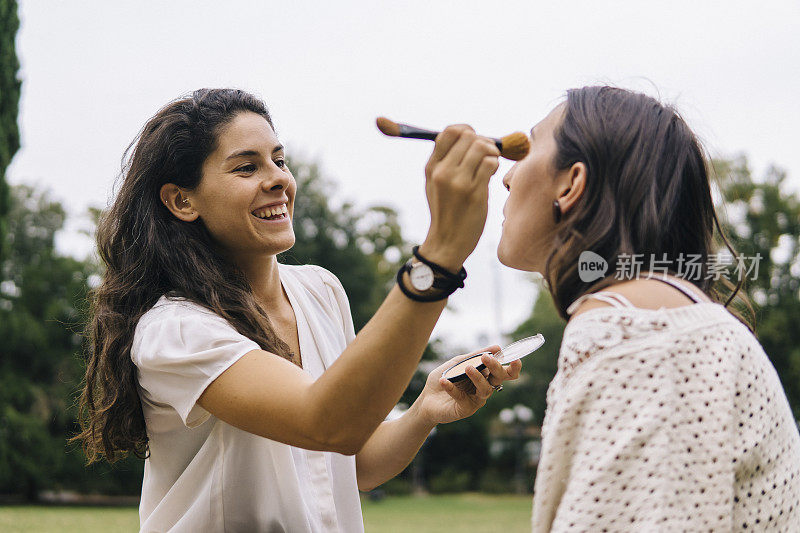 一对年轻女子在公园的户外化妆