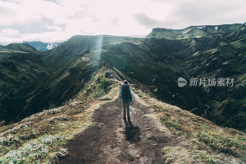 在冰岛的Landmannalaugar，一名妇女在彩色山脉附近徒步旅行