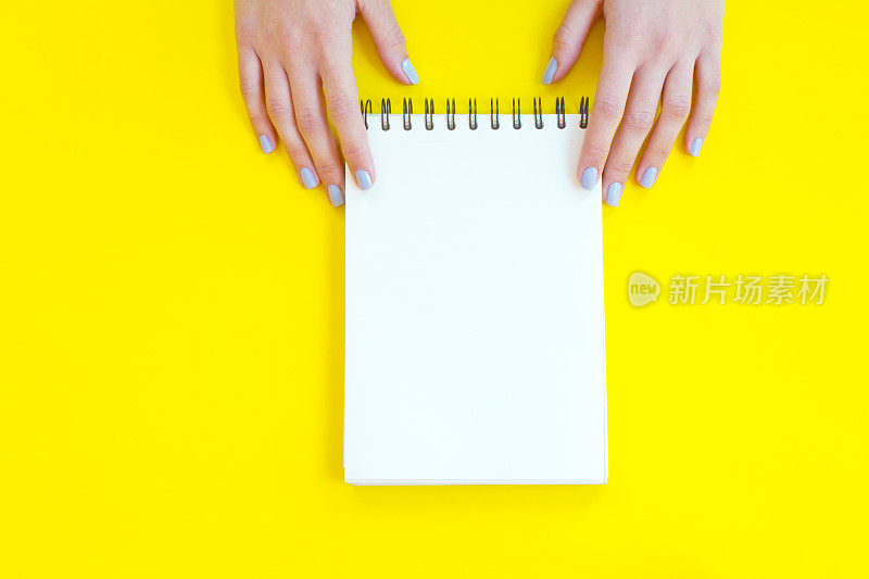 一个女人手里拿着黄色背景的笔记本。