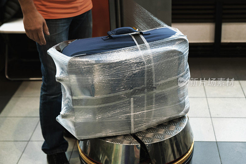 旅行前在机场额外打包行李，工作人员用透明薄膜包裹手提箱。