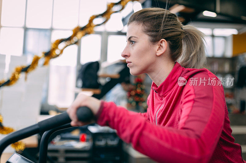 年轻的金发女郎在健身房骑车