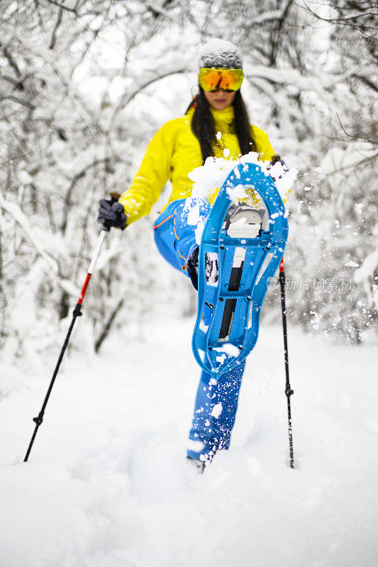 女徒步旅行者穿雪鞋穿过一个奇妙的冰冻森林