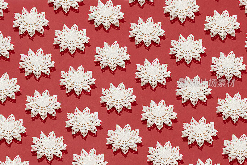 白色的雪花圣诞装饰平放在红色的背景上