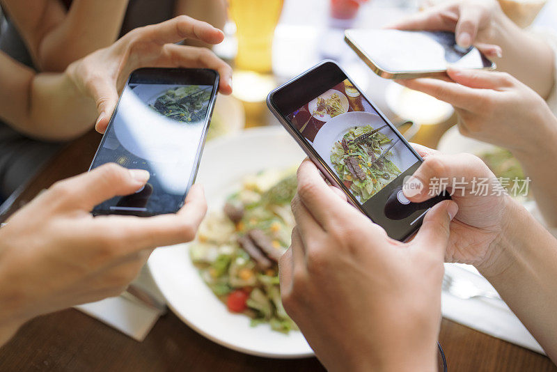 人们在饭前用智能手机拍照。前视图。