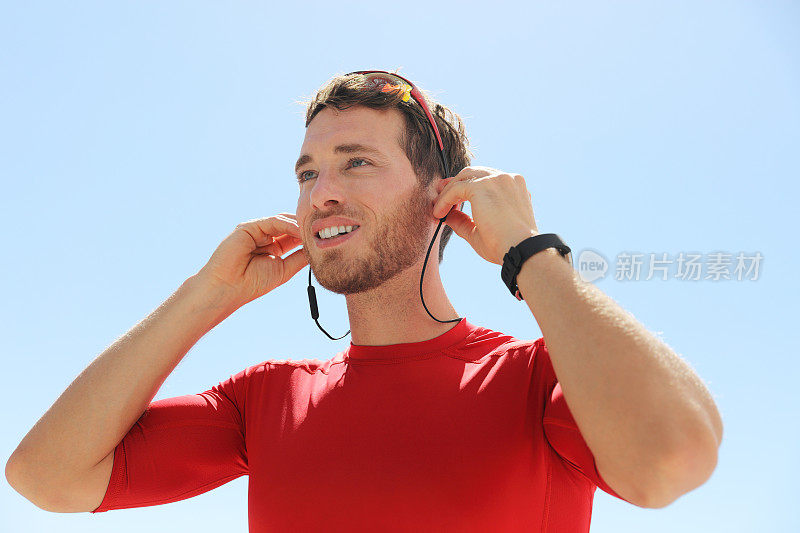 准备跑步的跑步者戴上无线耳机，无线耳机，智能手机通讯，在跑步锻炼时听音乐。快乐的运动员。