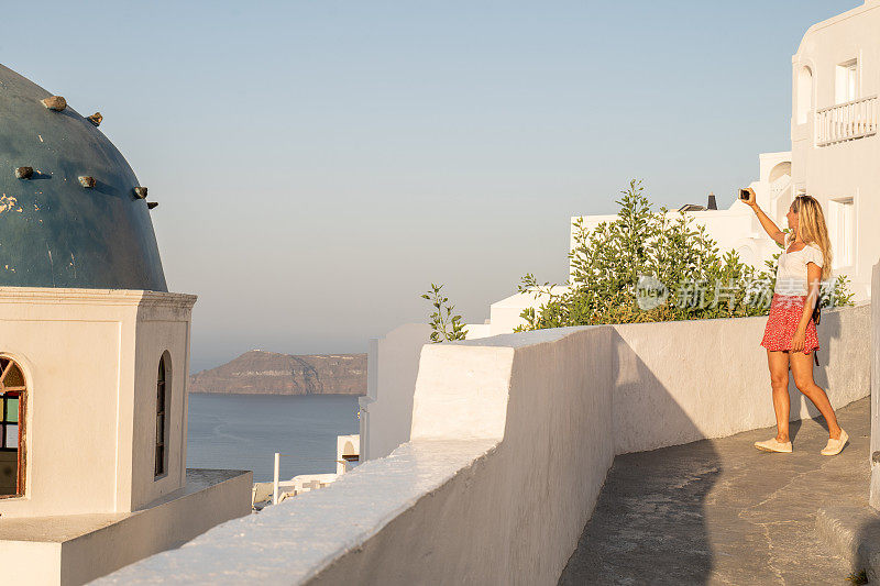 一名年轻女子在希腊观光，用手机拍照