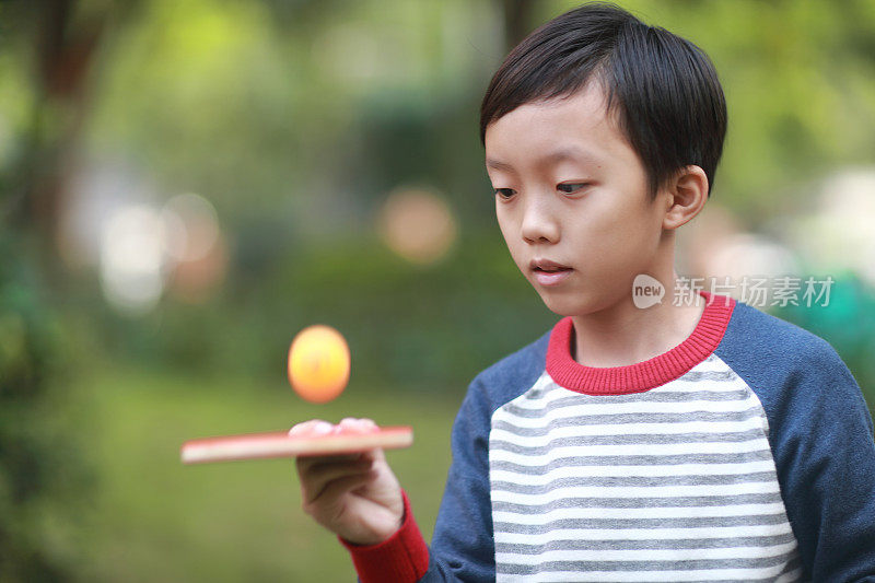 微笑的男孩在花园里打乒乓球