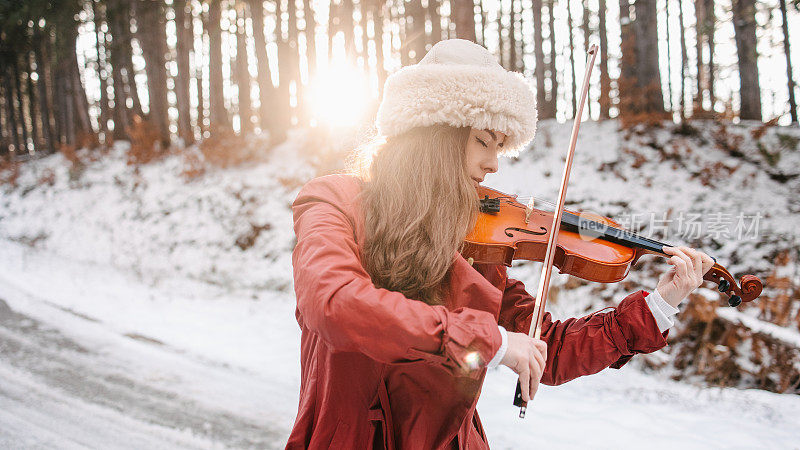 一位年轻女子在一个下雪天拉小提琴