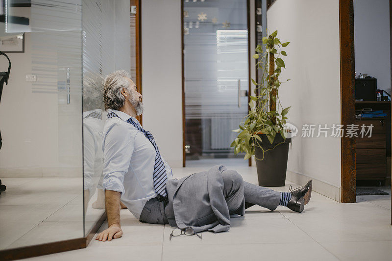 上了年纪的高级商人在办公室里工作很辛苦，感到筋疲力尽
