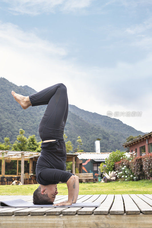 一个女人在山上的木地板上倒立。