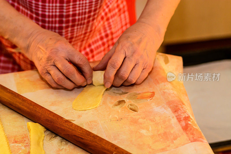 一位年长的妇女正在准备做香肠卷。