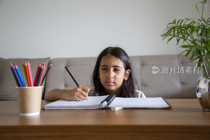 一个小女孩在家里的书桌上做作业