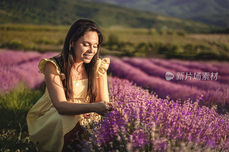 穿着白色连衣裙的女人在夕阳下走过薰衣草田