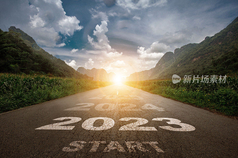 2023，新年2023或2023这个词的开始的概念写在柏油路中间的路上，夕阳的山景背景，规划的概念和挑战