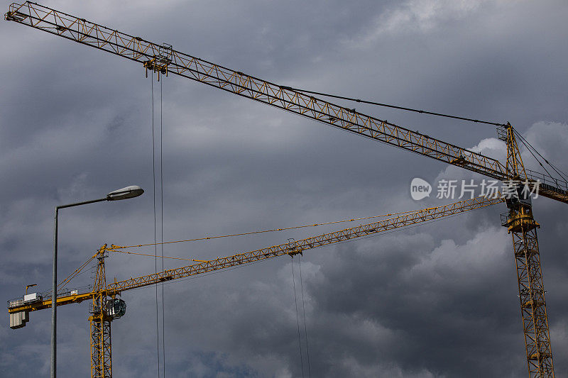 多云天空下建筑工地的两台起重机