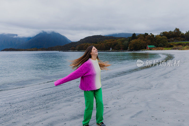 快乐的女人在挪威的海边和山景思索着秋天的时光