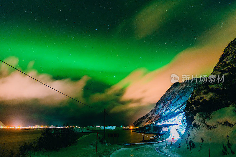 令人惊叹的北极光在北方的展示，一个明亮的绿色乐队在天空中跳舞，下面是一个令人惊叹的小木屋。