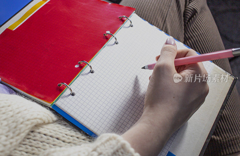 女人用铅笔在笔记本上写作业