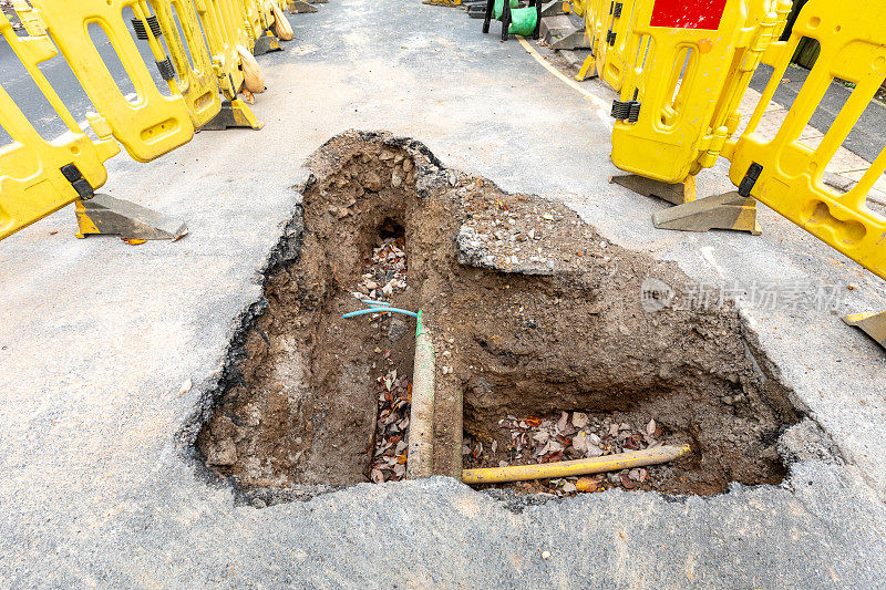 英国的道路工程正在挖掘当地的柏油路面，以修复地下的公用管道，并设置安全屏障和标志