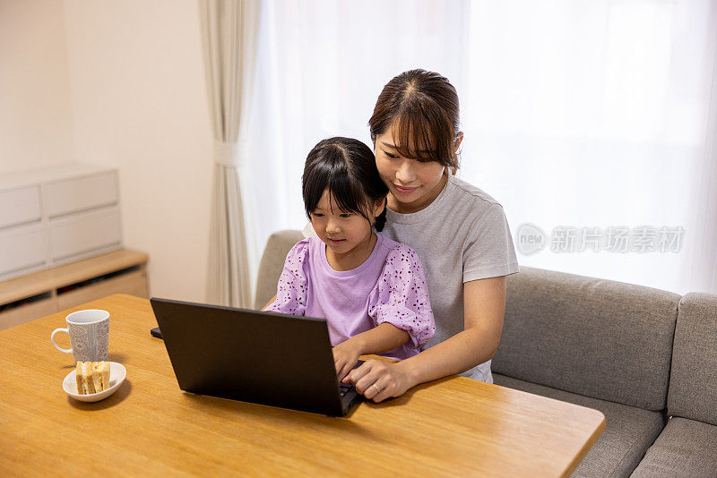 妈妈和妹妹在家里用笔记本电脑学习