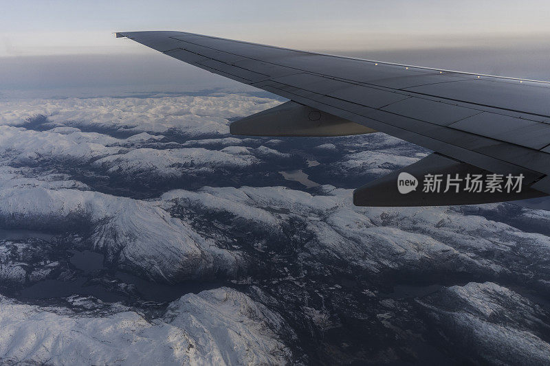 乘客从飞机上俯瞰挪威峡湾，山上覆盖着雪