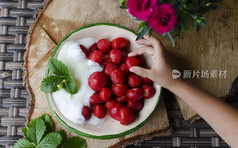 草莓在孩子的手里就这样准备吃。含有维生素的健康食品。生水果在碗里。特写镜头。