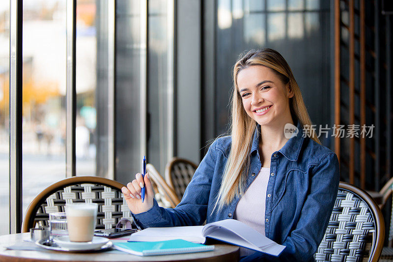 自信的优雅:金发女人自信的微笑，手里拿着笔