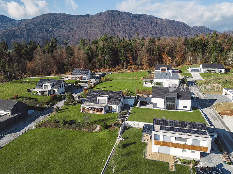 低空近景新密集农村住宅开发，大多是灰色屋顶，一些绿色景观，小树。有平屋顶的现代住宅