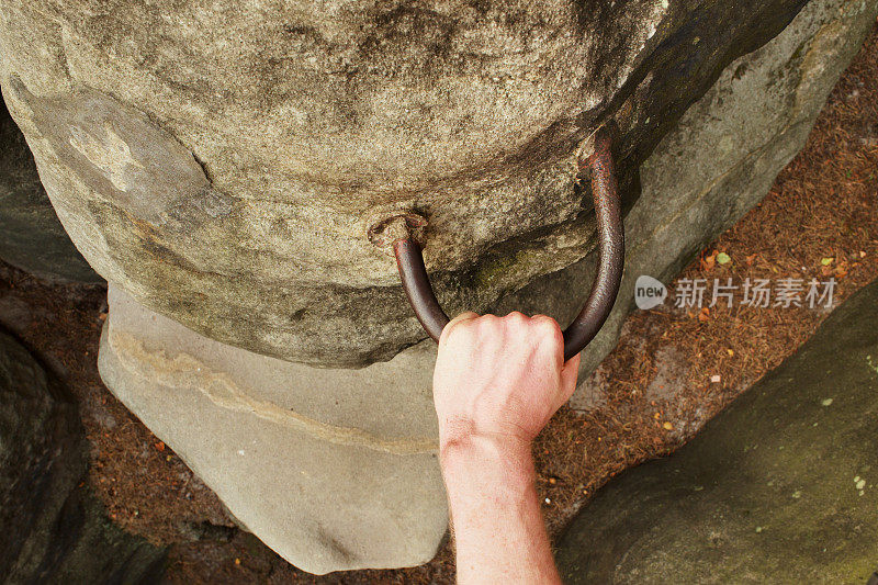 攀岩者的手放在固定在岩石上的钢把手上。