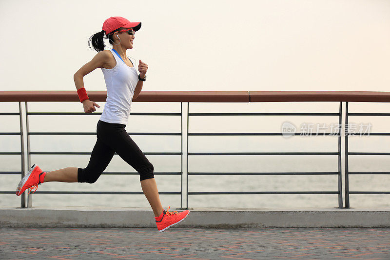 年轻的健身女性跑步在日出的海边
