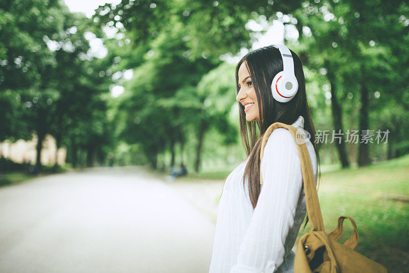 年轻漂亮的女学生在公园里听音乐