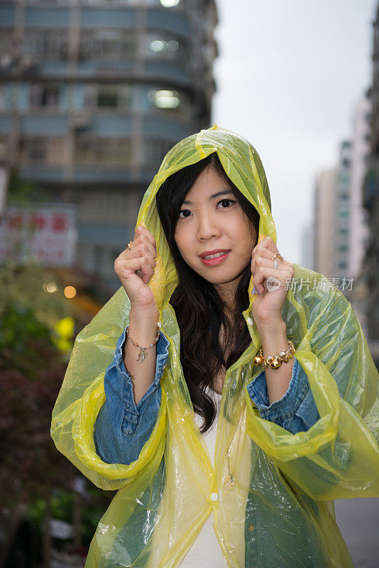 快乐的香港女人穿着雨衣不高兴在雨中