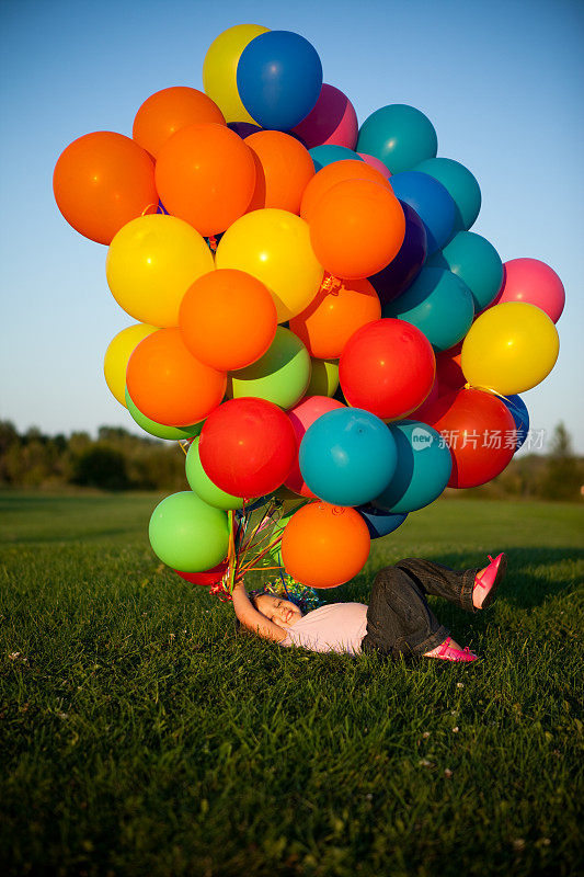 快乐的小女孩在外面拿着一堆气球