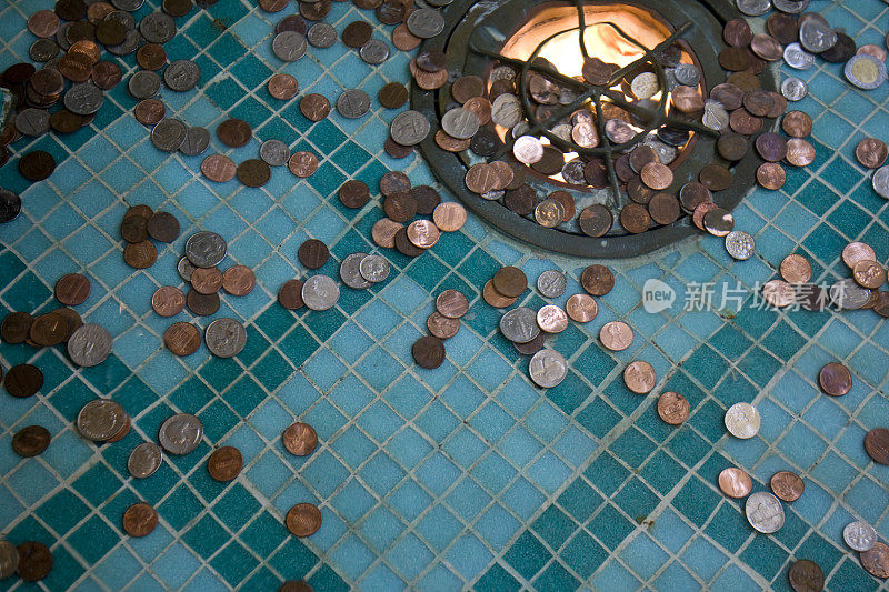 蓝色瓷砖地板上装满硬币的许愿井